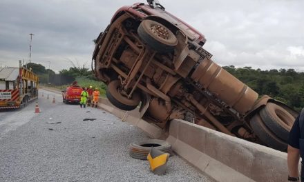 Carreta carregada com cimento tomba e fica pendurada em mureta na BR-381, em Betim