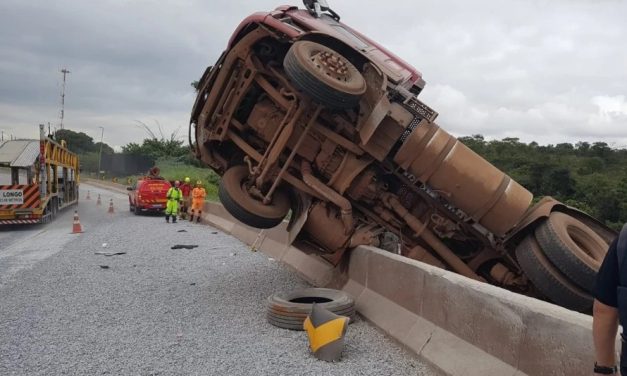 Carreta carregada com cimento tomba e fica pendurada em mureta na BR-381, em Betim