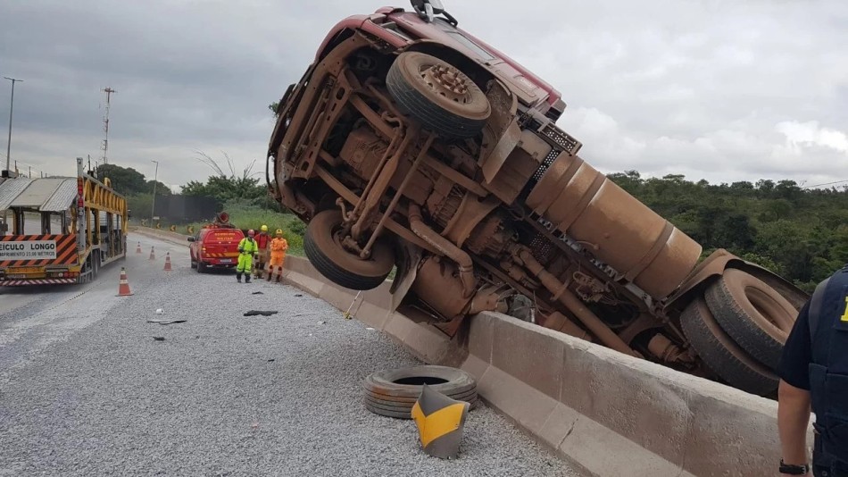 Carreta carregada com cimento tomba e fica pendurada em mureta na BR-381, em Betim