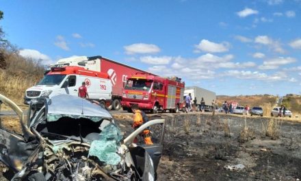 Motorista bate em caminhão e fica presa às ferragens com carro em chamas