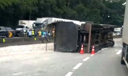 Carreta com garrafas de vidro bate em barreira de concreto e tomba na Fernão Dias