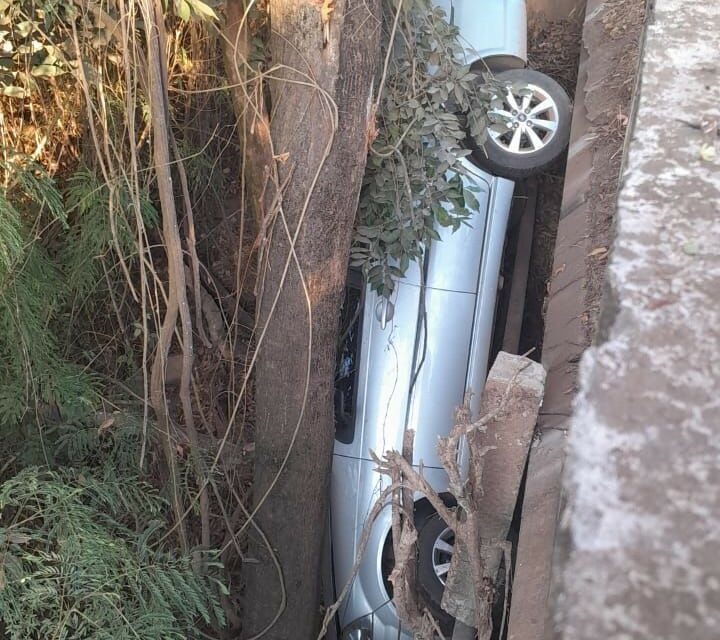 Carro cai em ribanceira e fica prensado entre mureta e árvore em Pitangui